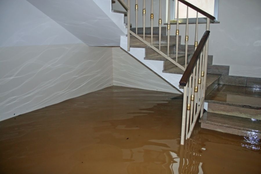Basement flooding damage showing standing water and damaged belongings