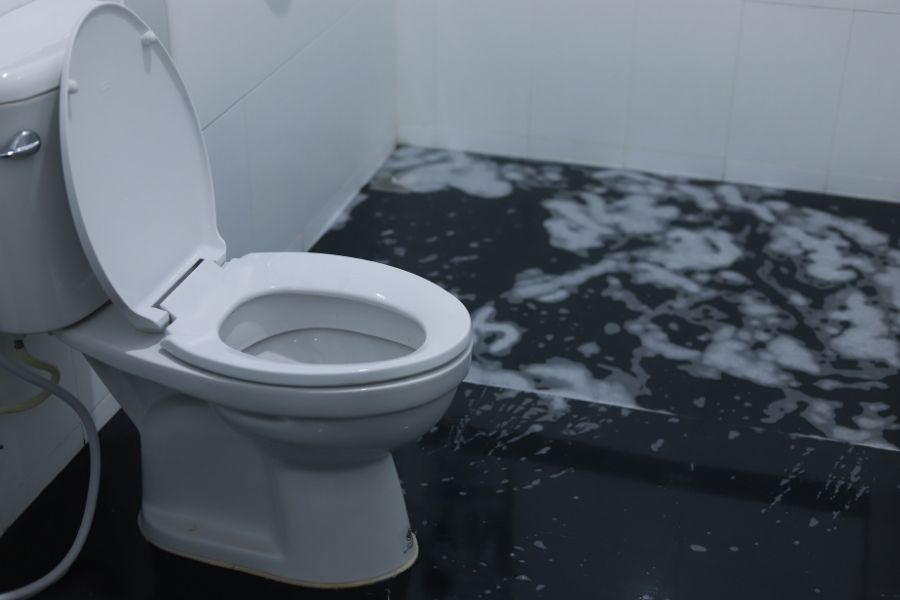 Toilet overflowing with water on bathroom floor