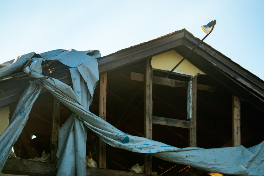 Blue emergency tarp covering fire-damaged roof