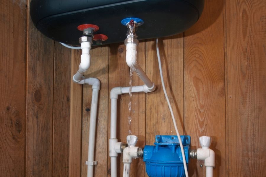 Homeowner shutting off water heater valve to stop leak