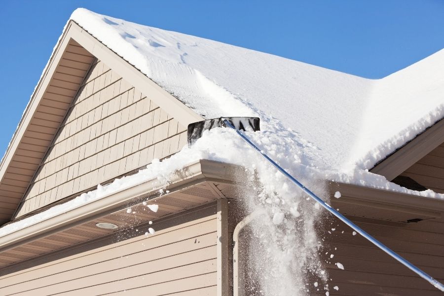 Snow rake removing snow from roof edge to prevent ice dams
