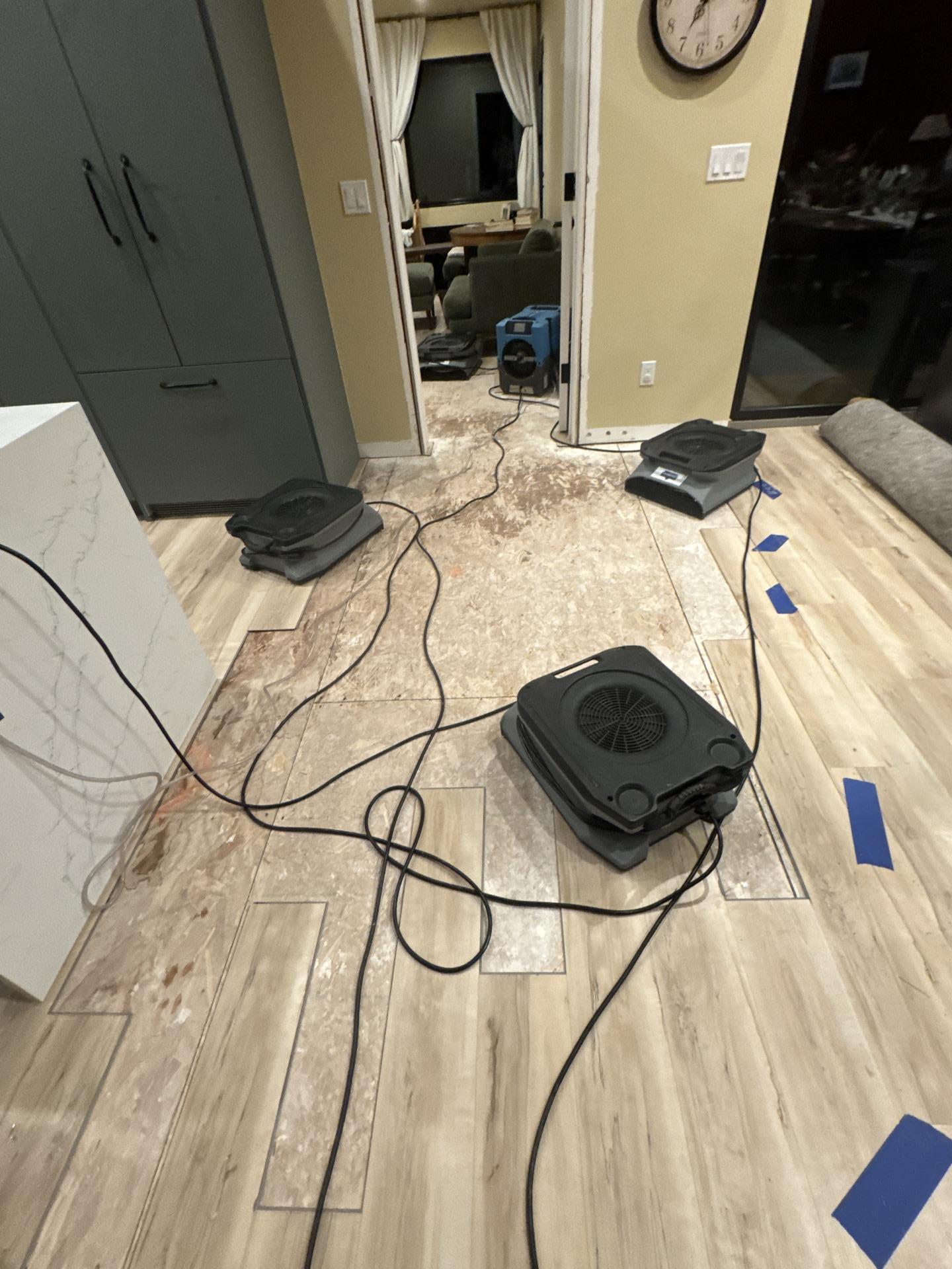 Exposed subfloor in kitchen with drying equipment running during structural water damage restoration