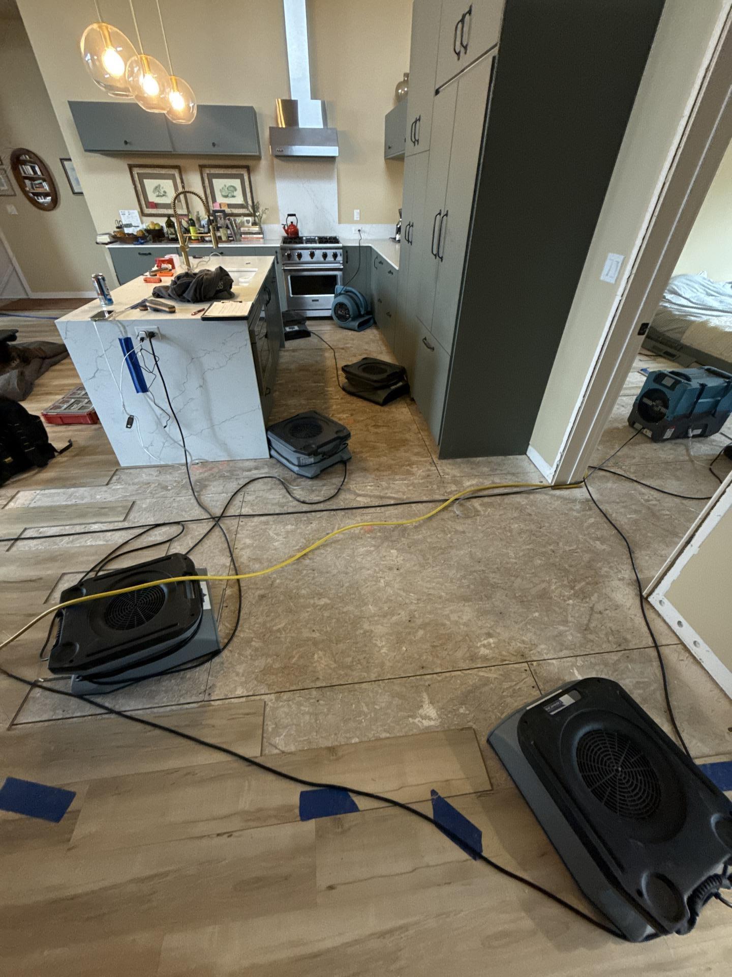 Air movers and dehumidifiers operating in kitchen during structural drying after water damage