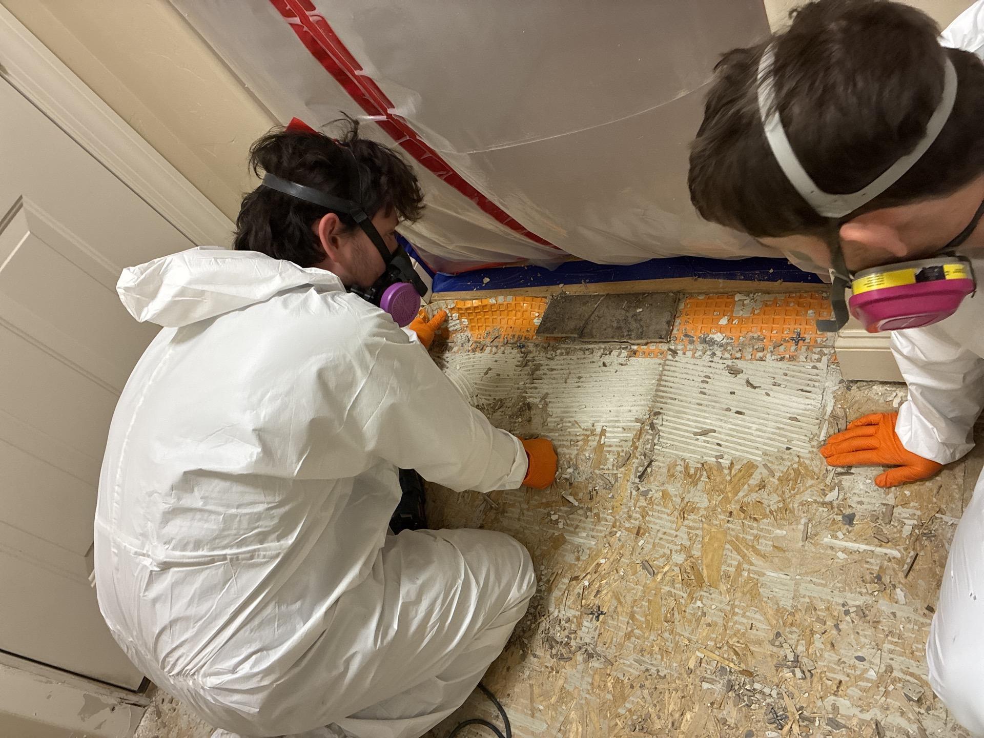 Tile removal during mold remediation to access saturated subfloor beneath flooring assembly