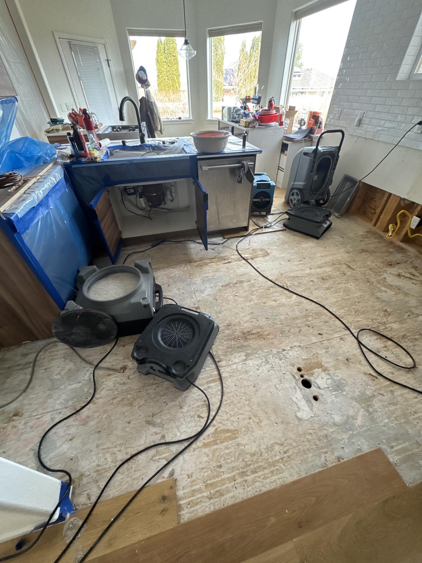 Kitchen water damage restoration progress with materials removed and drying
