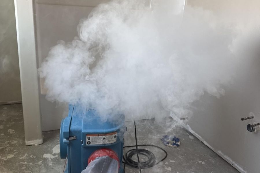 Technician running thermal fogging equipment during a professional smoke and soot cleanup