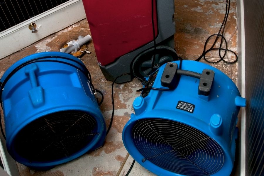 Professional drying and air movement equipment set up on a bathroom floor during sewage backup mitigation