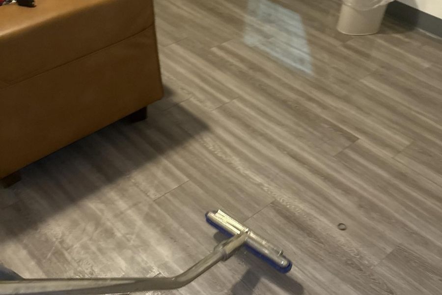 Technician extracting standing water from a flooded living room carpet