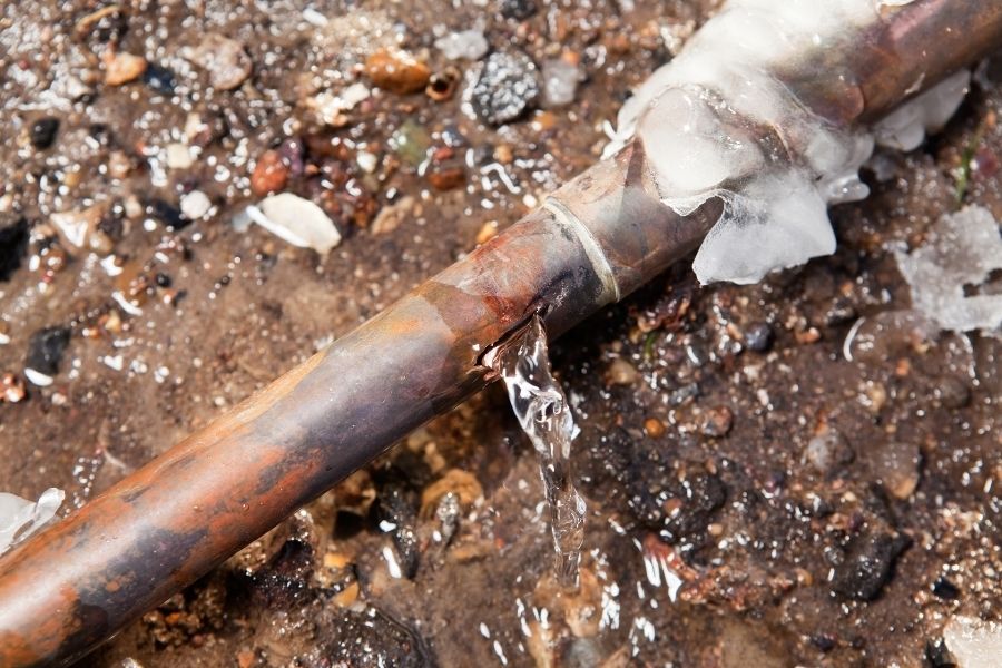 Frozen copper water pipe with ice buildup in an unheated space during winter