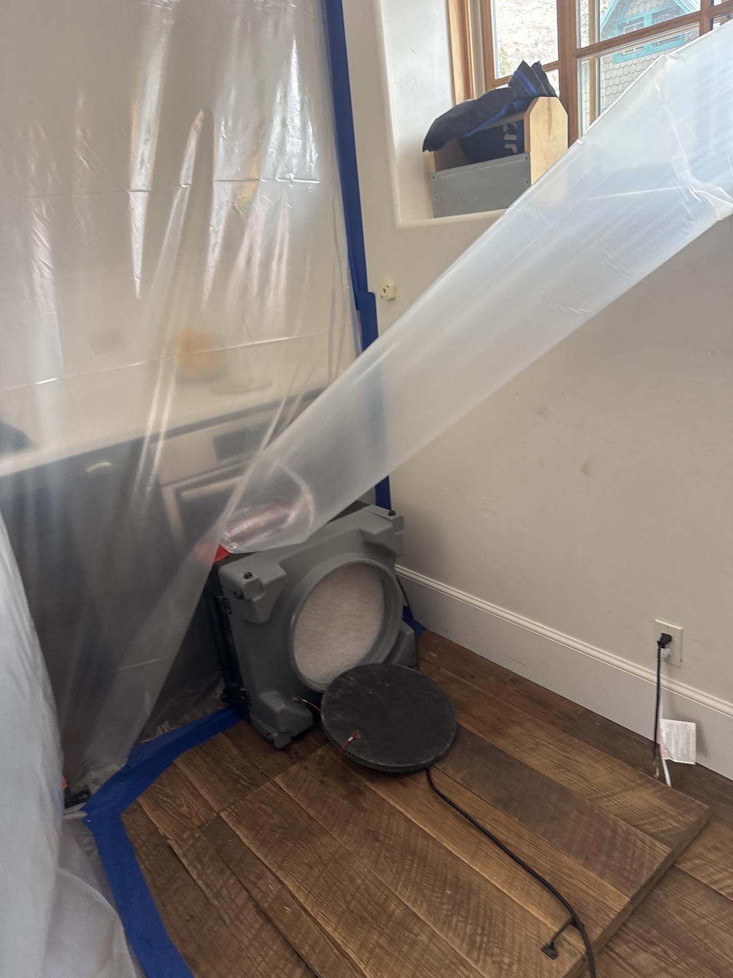 Technician working inside a controlled containment chamber near the kitchen crawlspace
