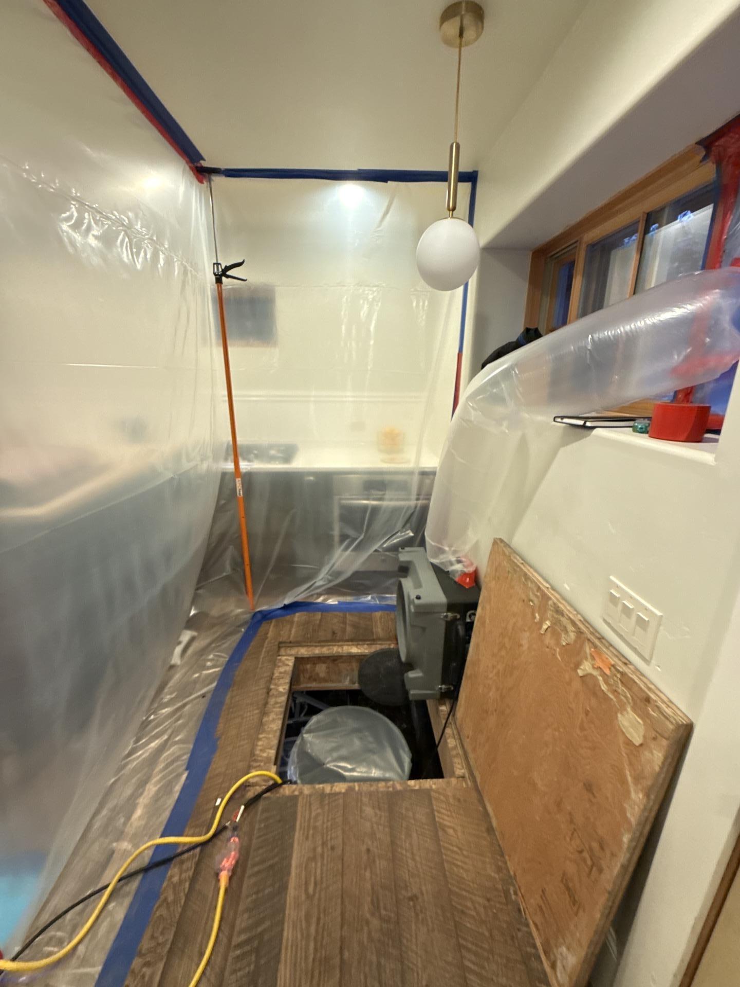 Sealed plastic containment protecting living areas during crawlspace mold remediation