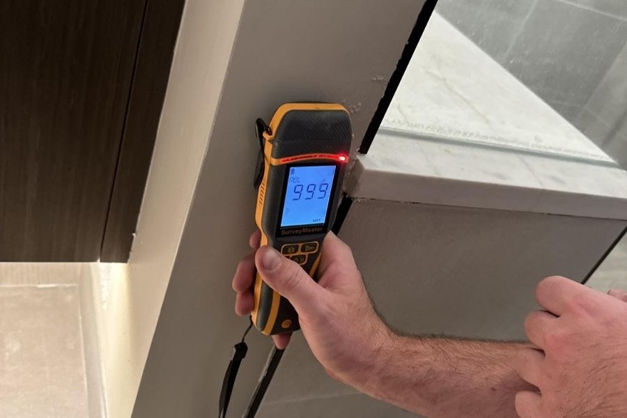 Moisture meter showing an elevated reading on a wall after water damage