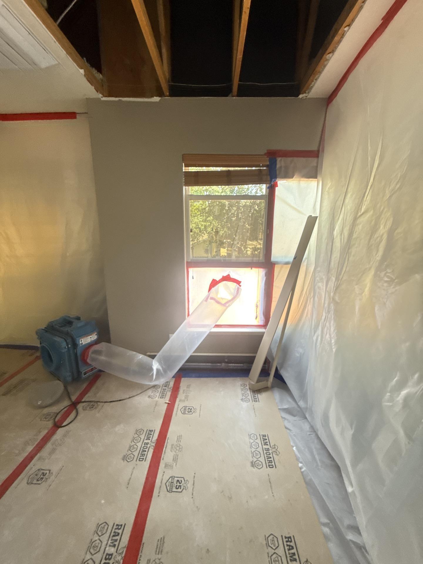 Technician HEPA vacuuming exposed framing during mold remediation